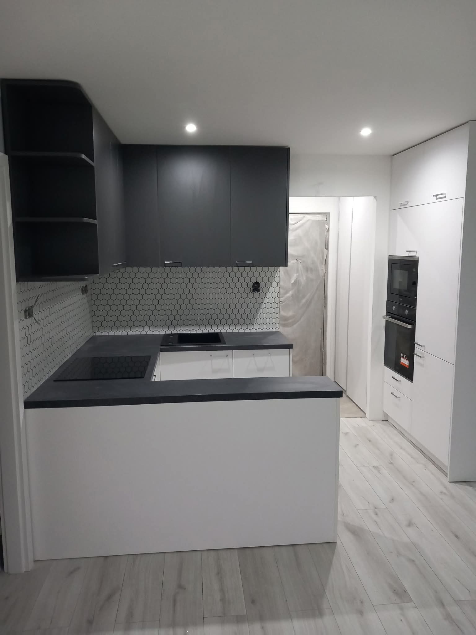 Biela kuchyňa s čiernou pracovnou doskou a hexagon obkladom