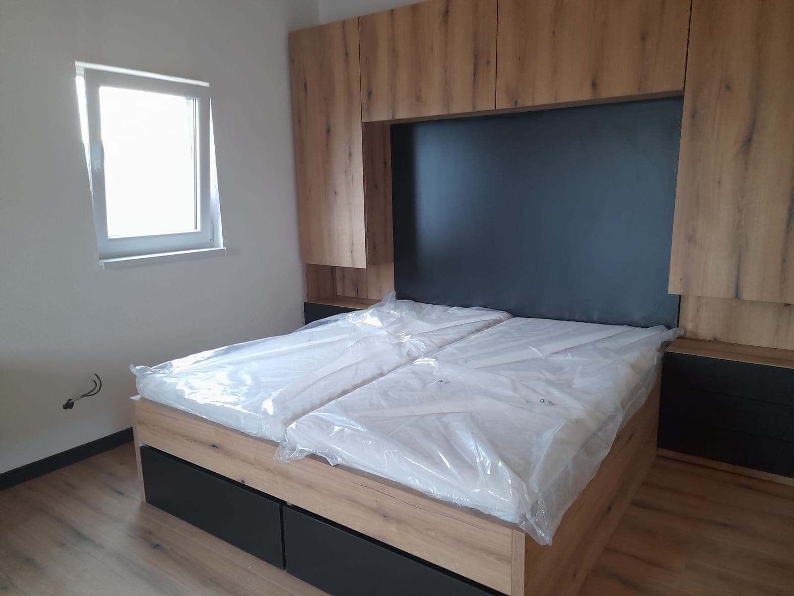 Spálňa s posteľou a skriňou v dreve a čiernej